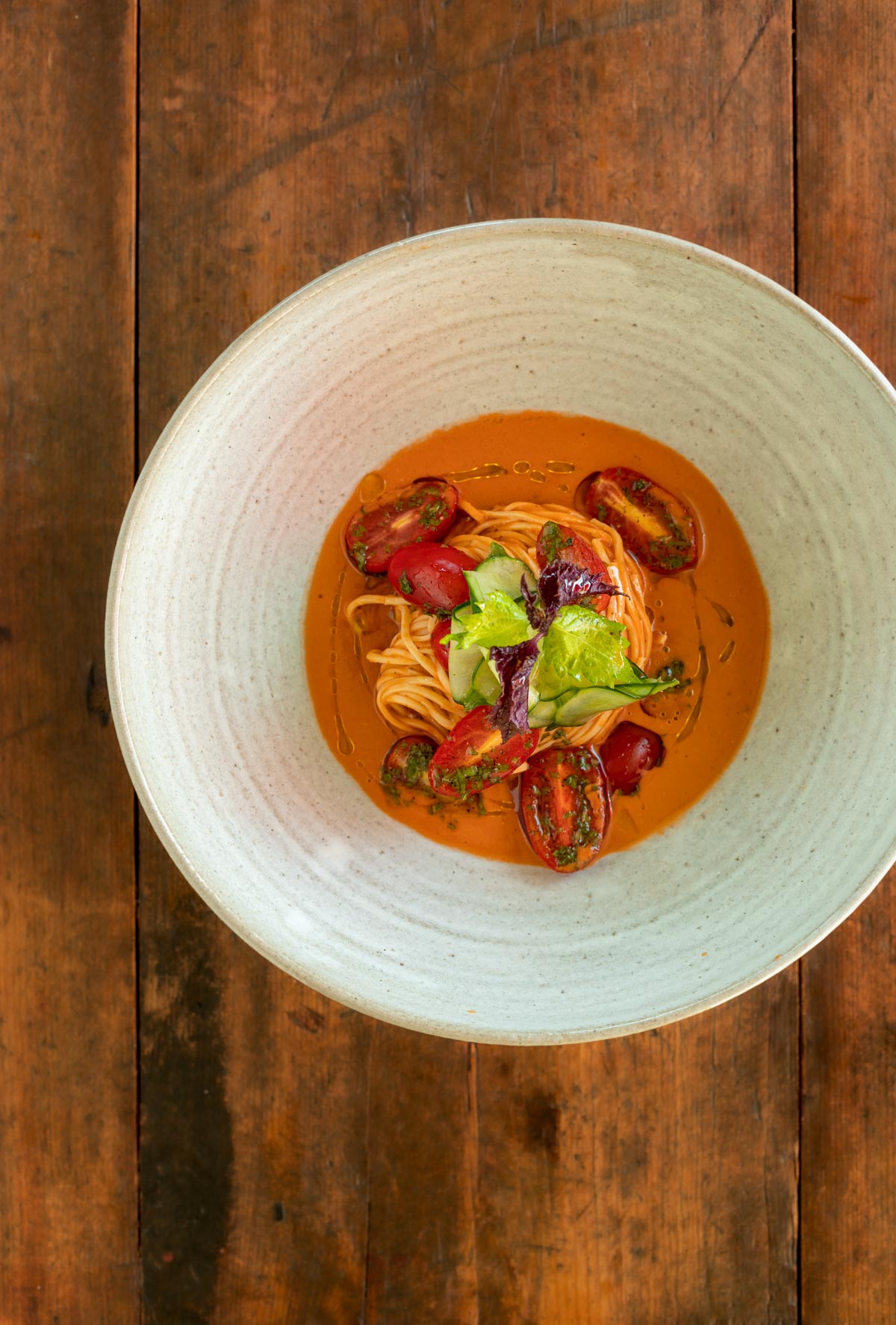 Capellini pasta in ceramic bowl on woonden table tomato
