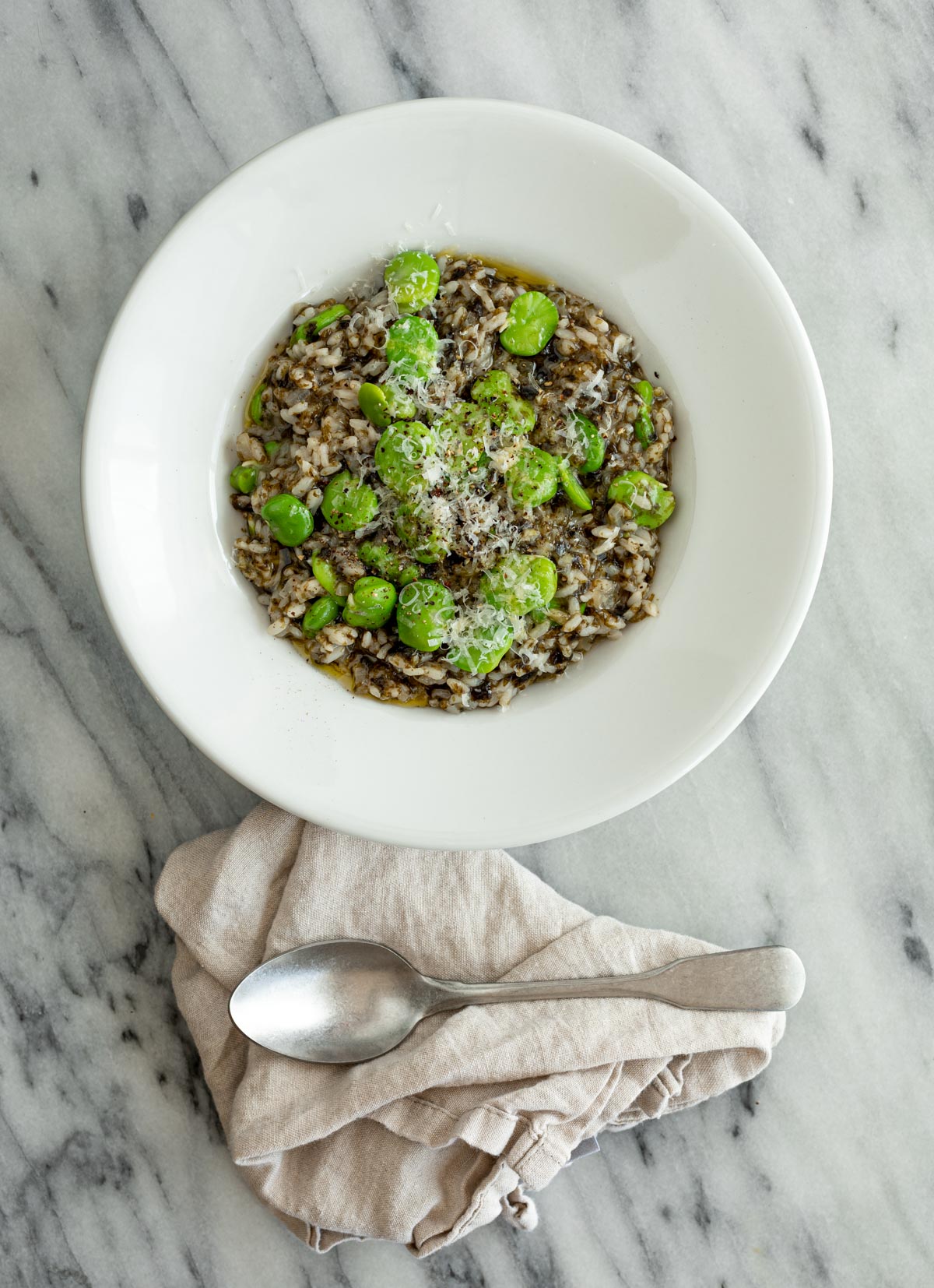 nori risotto with fava bean with fork and nakin on marble table